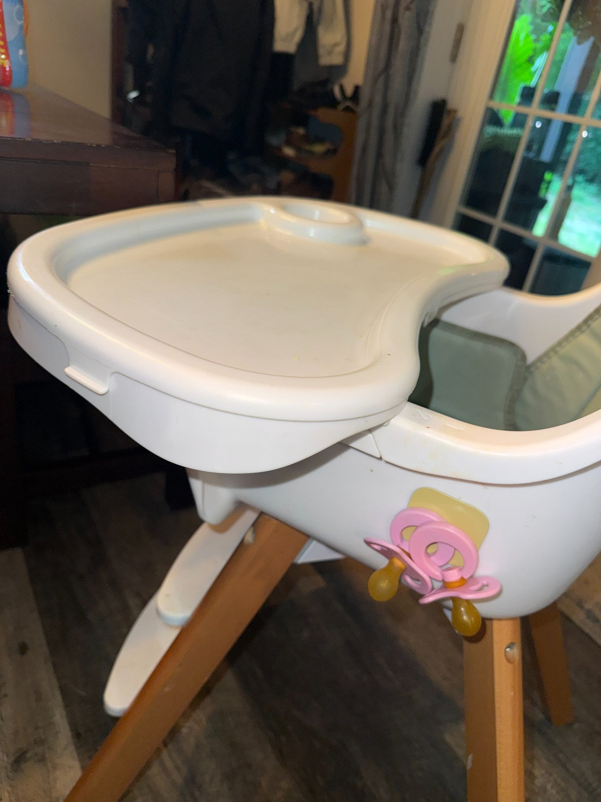 Blush Magnetot pacifiers attached beside a family high chair