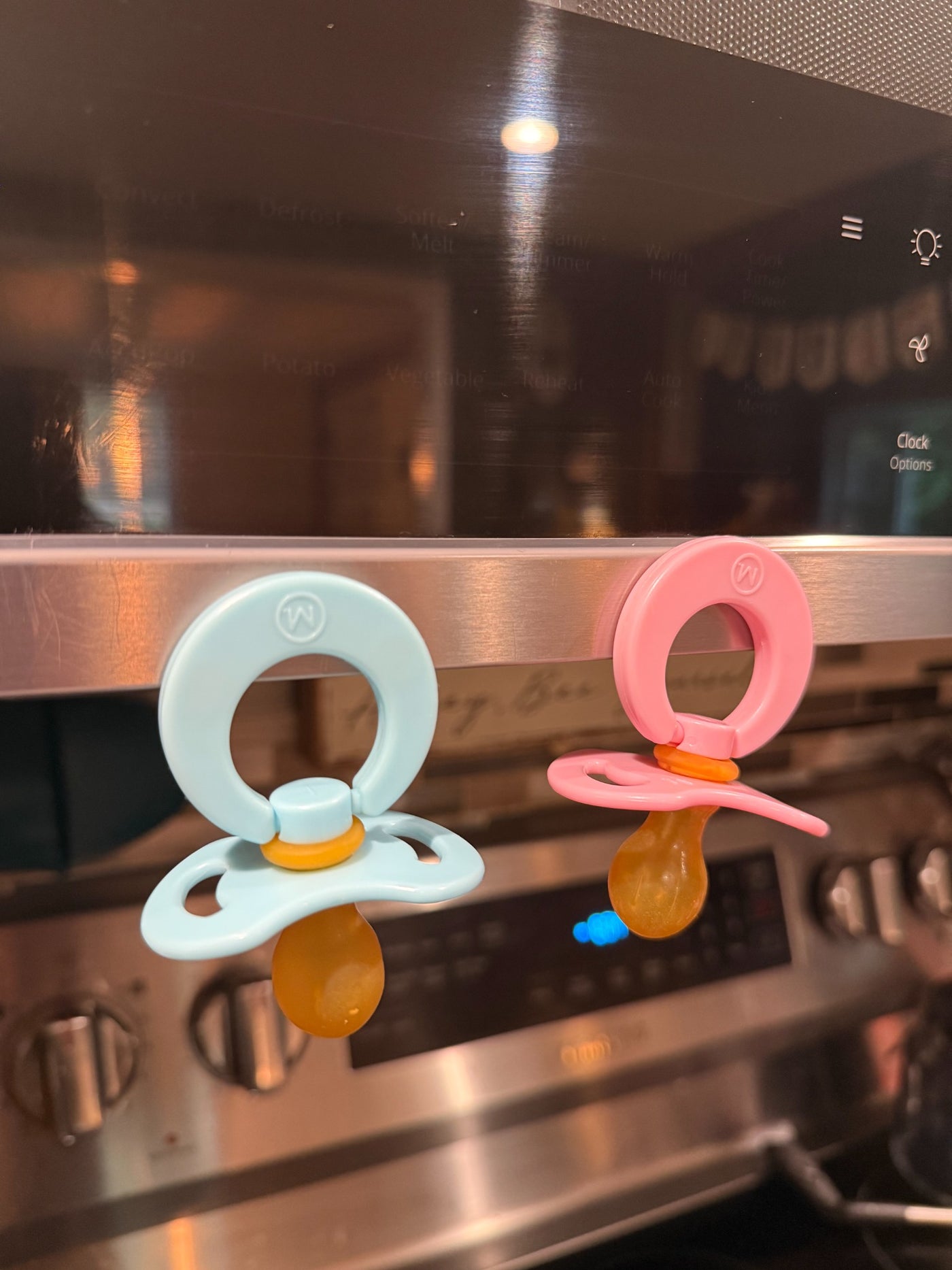 Sky and Blush Magnetot pacifiers visible on a kitchen appliance